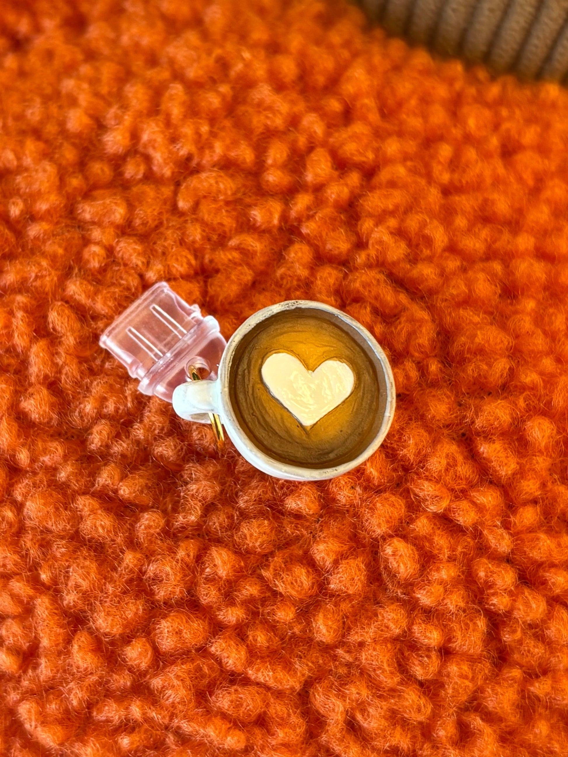 Close-up of a small round object with a heart design on an orange textured surface.